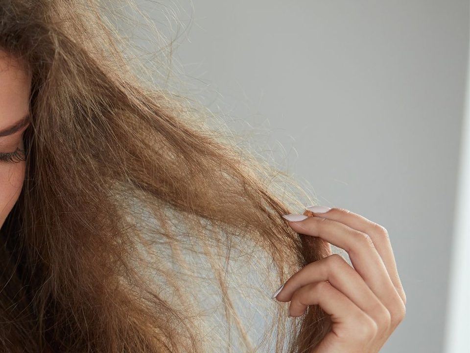 Femme tenant une mèche de cheveux longs secs et emmêlés